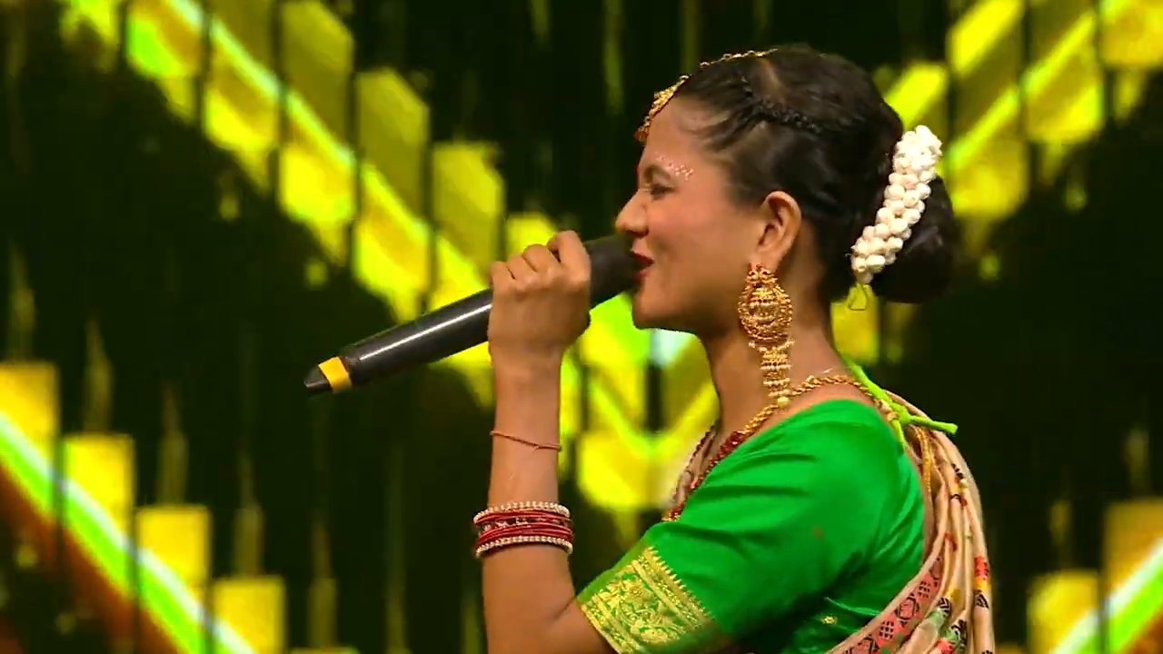 Barnali Hota singing in a green saree with traditional jewellery